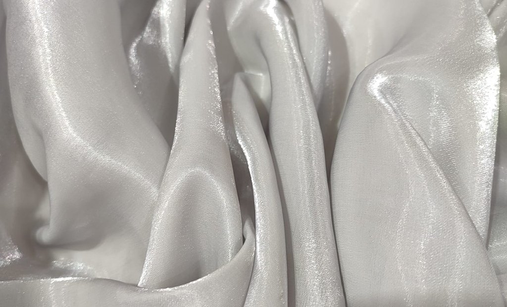 Close-up of lustrous metallic organza fabric with soft, flowing folds and a subtle sheen that reflects light. Metallic Organza Fabric