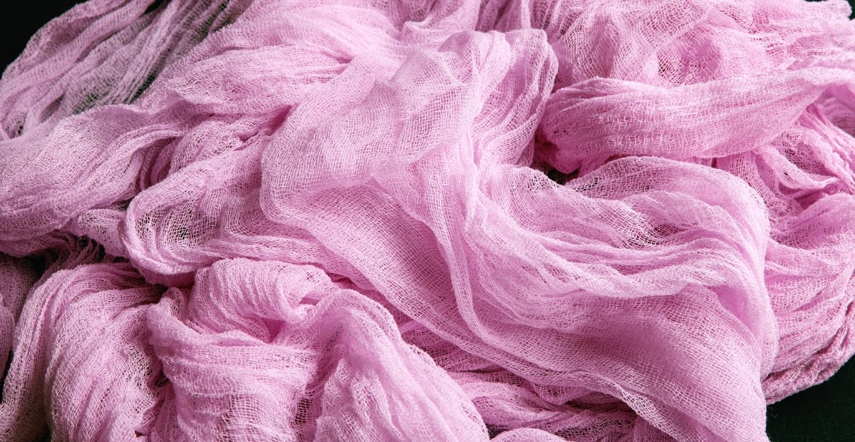 Soft pink fabric draped in folds and ruffles.