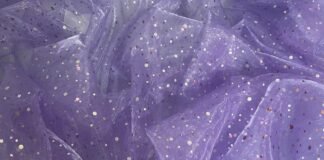 Discover the Magic of Glitter Organza Fabric for Fashion A soft lavender sheer fabric with small iridescent sequins scattered across its surface.