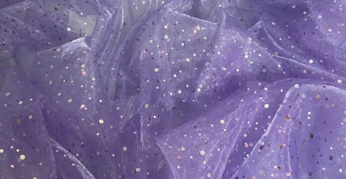 A soft lavender sheer fabric with small iridescent sequins scattered across its surface.