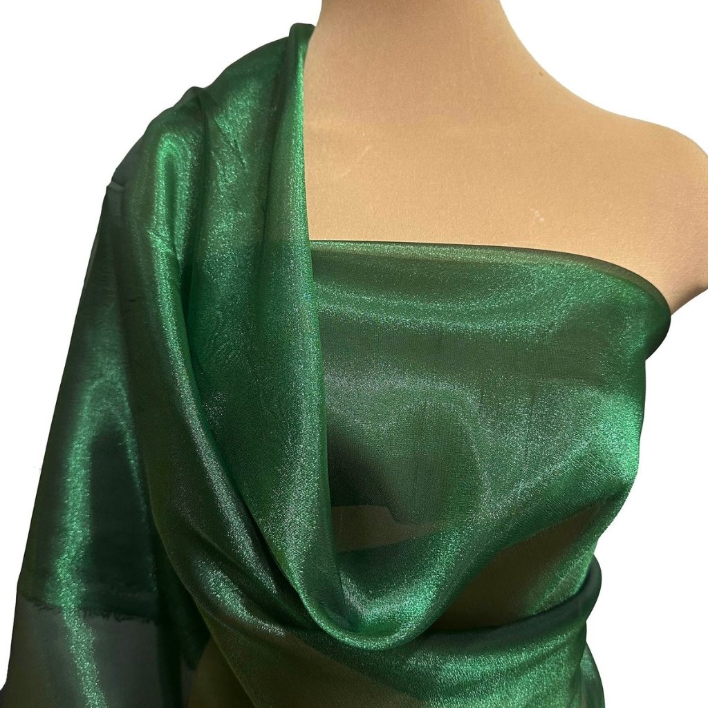 Green Organza Fabric: Elegant Choices for Fashion and Decor 12 Close-up of a green satin fabric draped over a shoulder and back of a mannequin, with a single-shoulder style and shiny, smooth texture