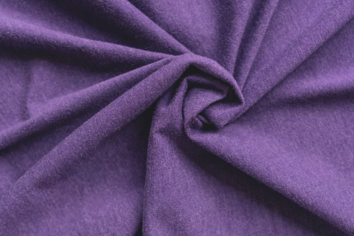“Close-up of purple rayon blend fabric twisted in the center, showing soft, smooth texture.