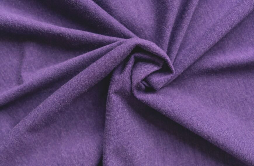 “Close-up of purple rayon blend fabric twisted in the center, showing soft, smooth texture.
