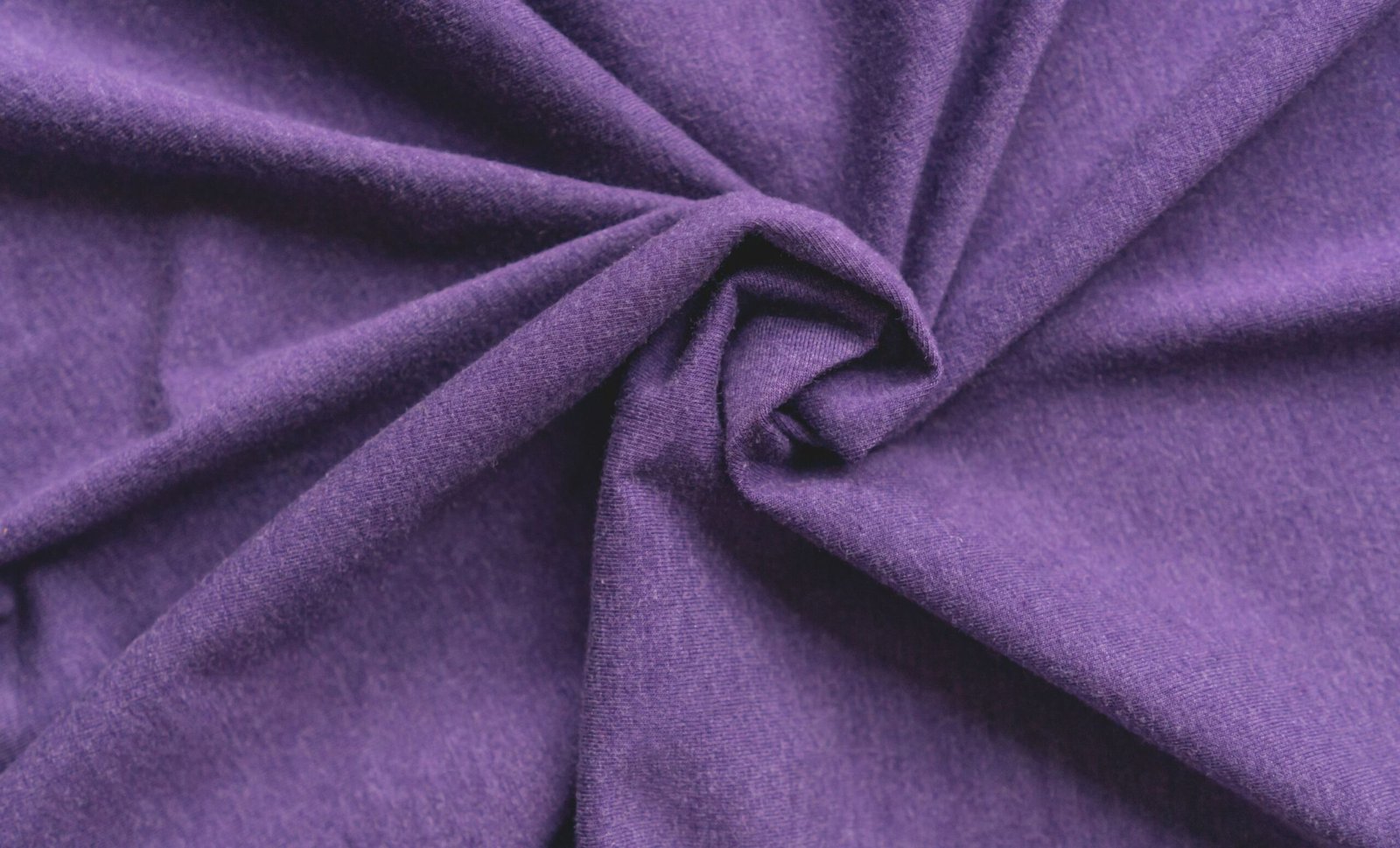 “Close-up of purple rayon blend fabric twisted in the center, showing soft, smooth texture.