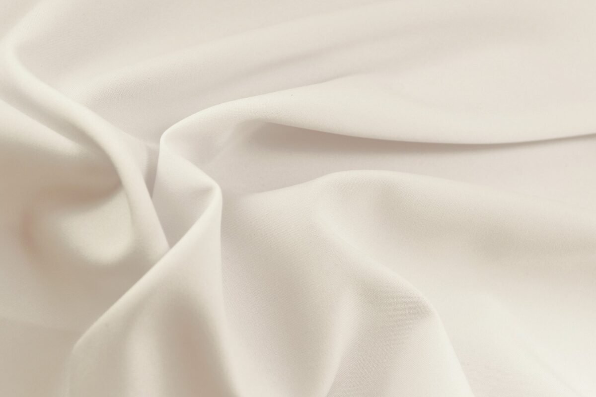 "Close-up of smooth, white rayon lawn fabric with soft folds and a matte finish."