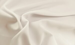 "Close-up of smooth, white rayon lawn fabric with soft folds and a matte finish."