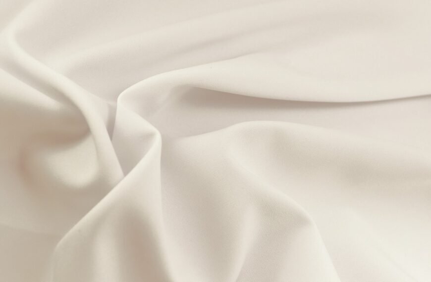 "Close-up of smooth, white rayon lawn fabric with soft folds and a matte finish."
