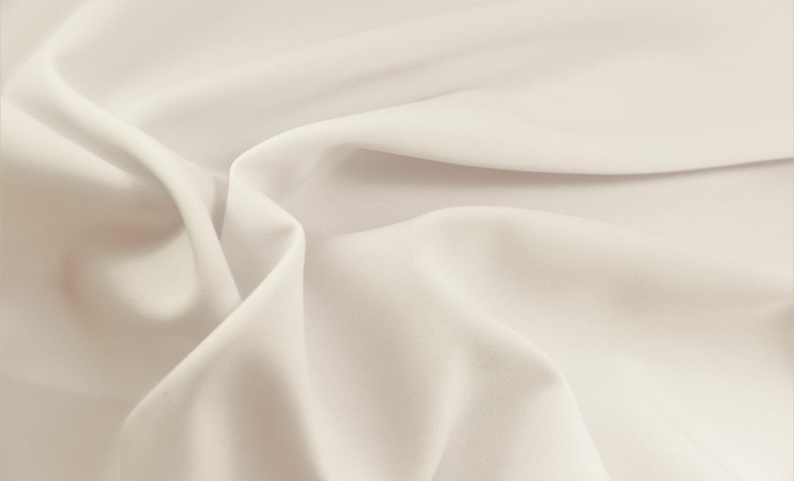 "Close-up of smooth, white rayon lawn fabric with soft folds and a matte finish."