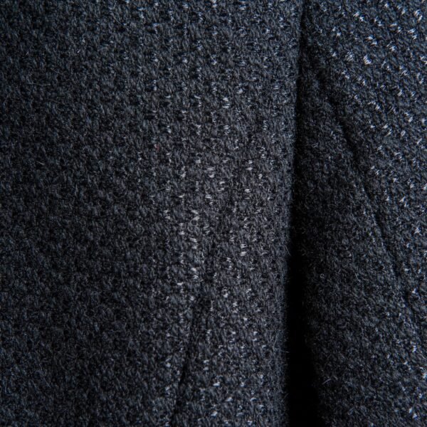 Close-up image of a dark, textured fabric with a speckled, boucle-like surface, showing a soft weave of rayon and nylon fibers.