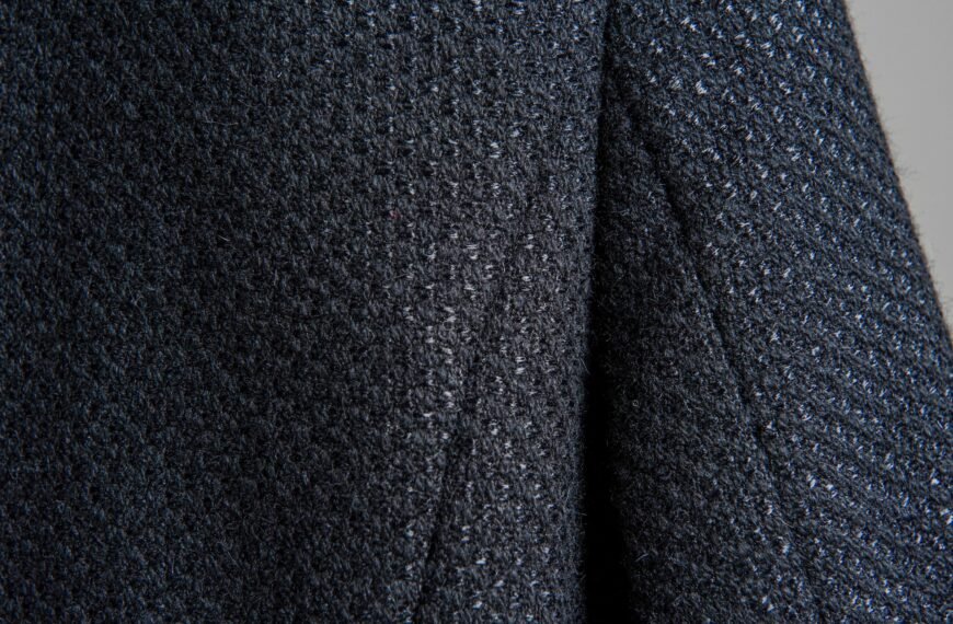 Close-up image of a dark, textured fabric with a speckled, boucle-like surface, showing a soft weave of rayon and nylon fibers.