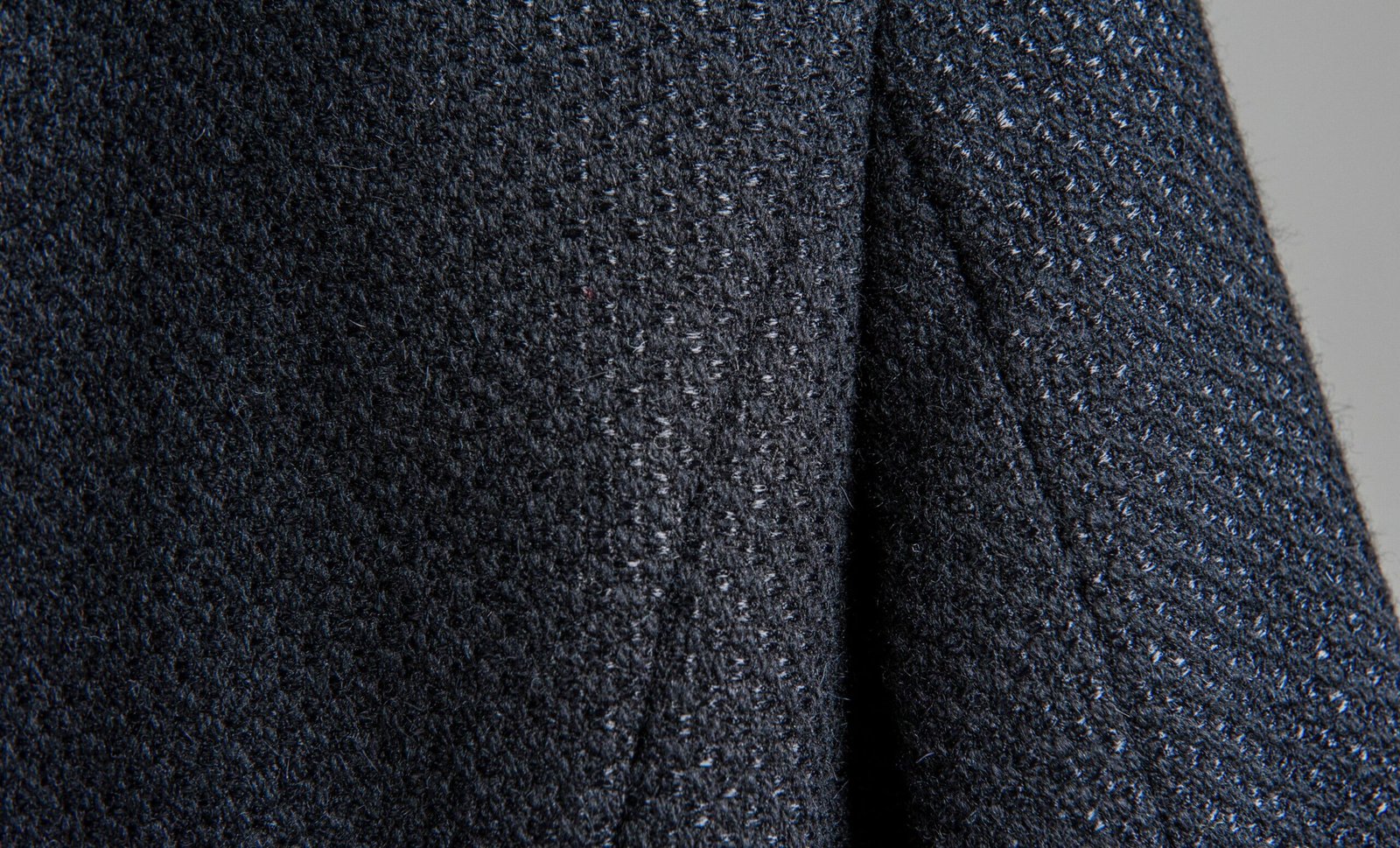 Close-up image of a dark, textured fabric with a speckled, boucle-like surface, showing a soft weave of rayon and nylon fibers.