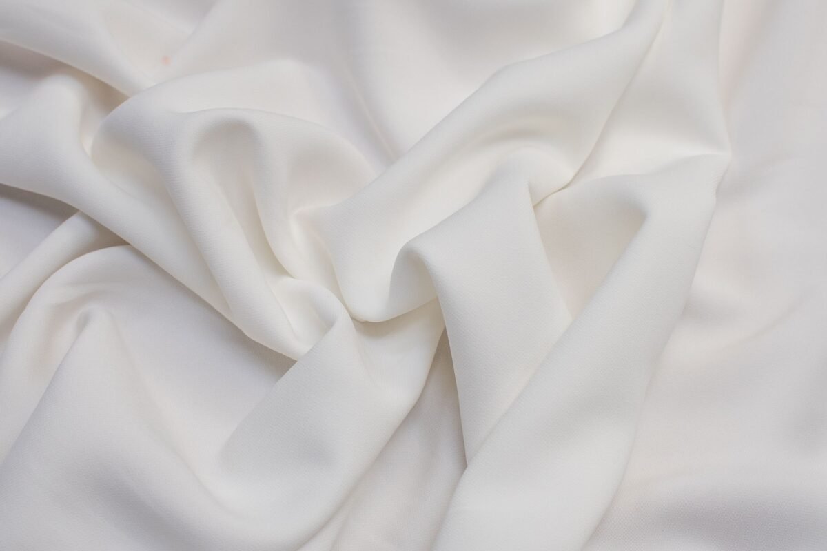 Close-up image of smooth, white Rayon Poplin fabric with soft, even weave and gentle folds."