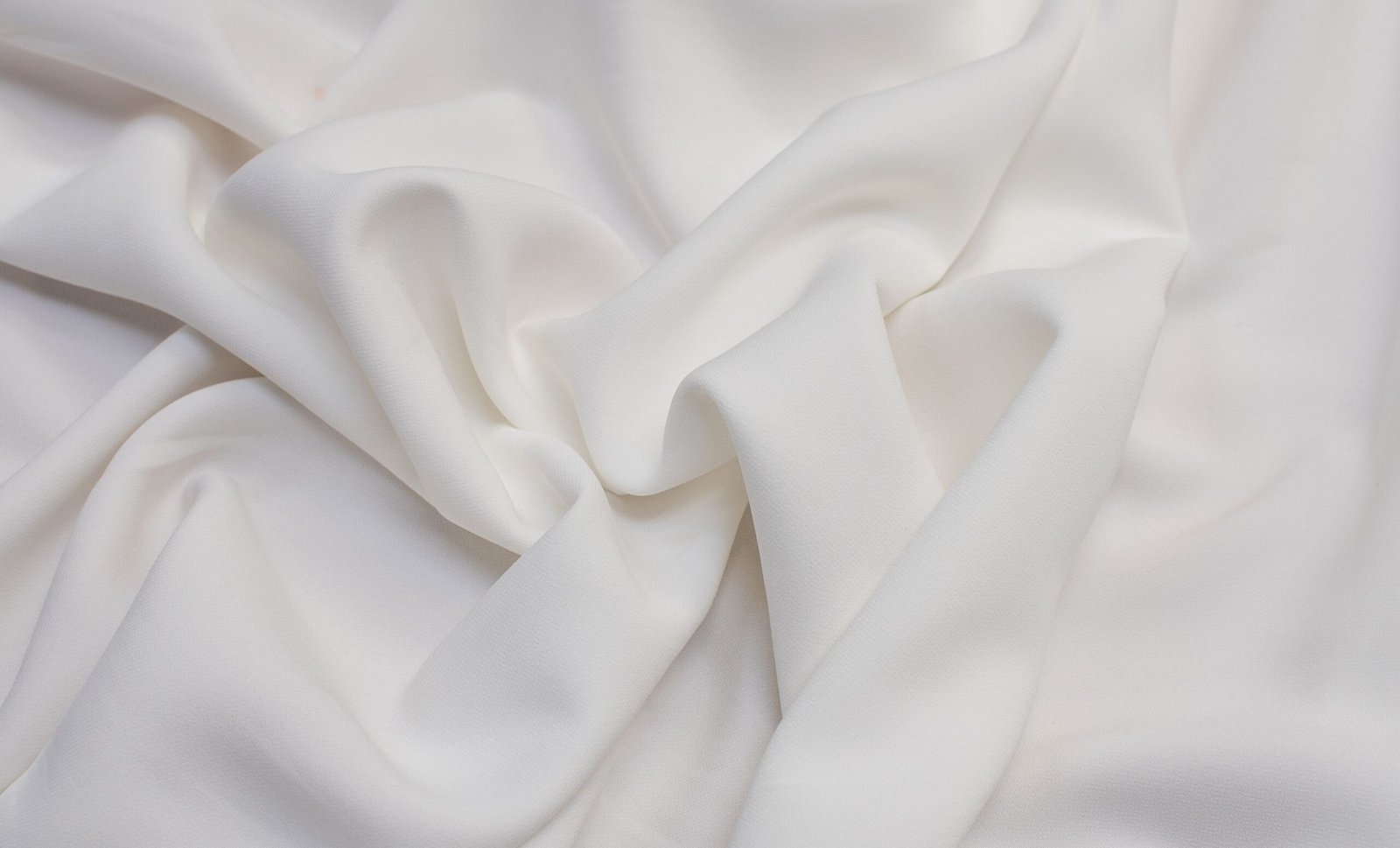 Close-up image of smooth, white Rayon Poplin fabric with soft, even weave and gentle folds."