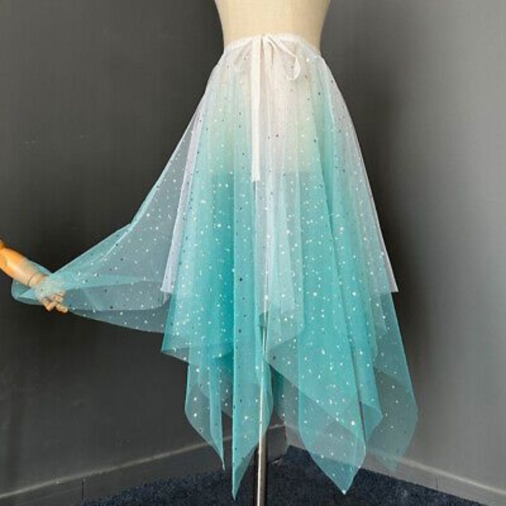 A flowing pastel ombre skirt in shades of aqua and white, made from layered sheer tulle with small white polka dots. The skirt is shown on a dress form, tied at the waist with a white ribbon.