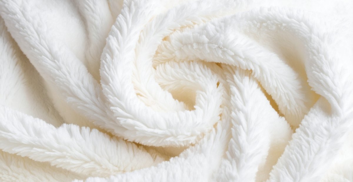 Close-up of soft, white, fluffy fabric with a plush, swirling texture.