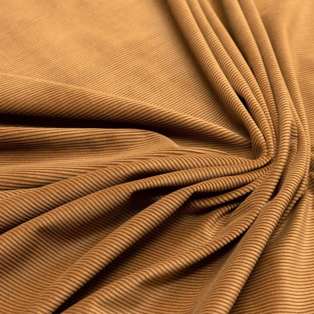 Close-up of brown corduroy fabric with visible ridged wales and soft folds.