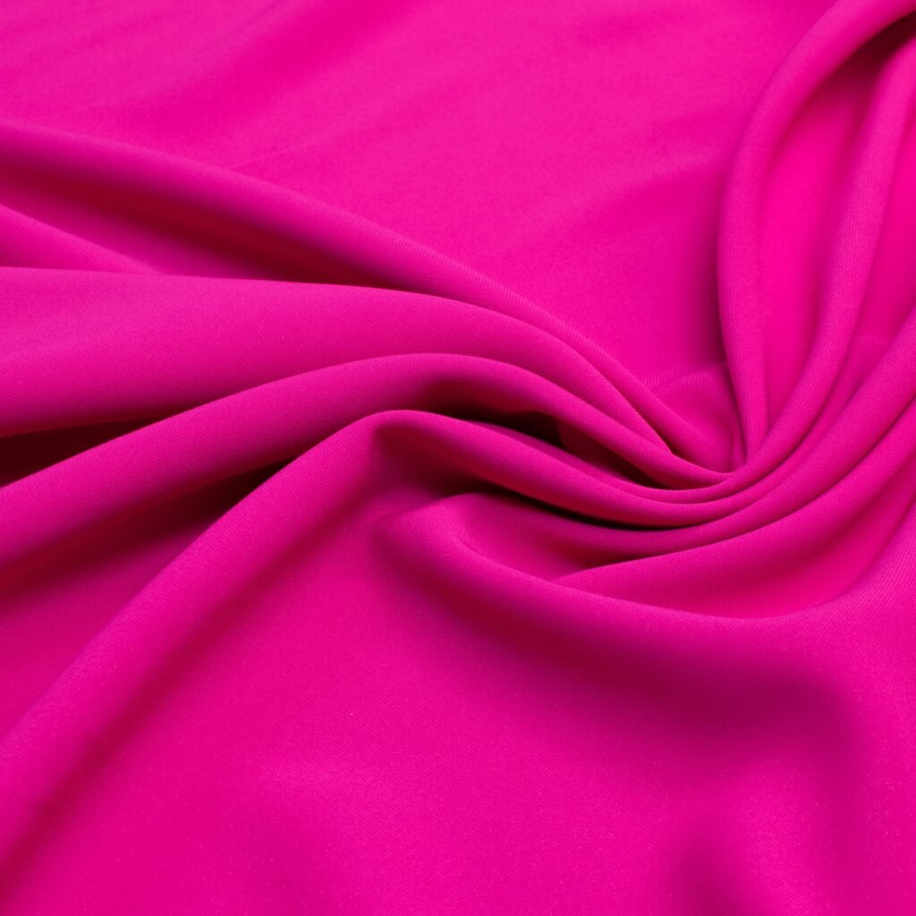 A vivid magenta rayon poplin fabric spread with soft folds and gentle sheen, showcasing smooth, tightly woven texture.