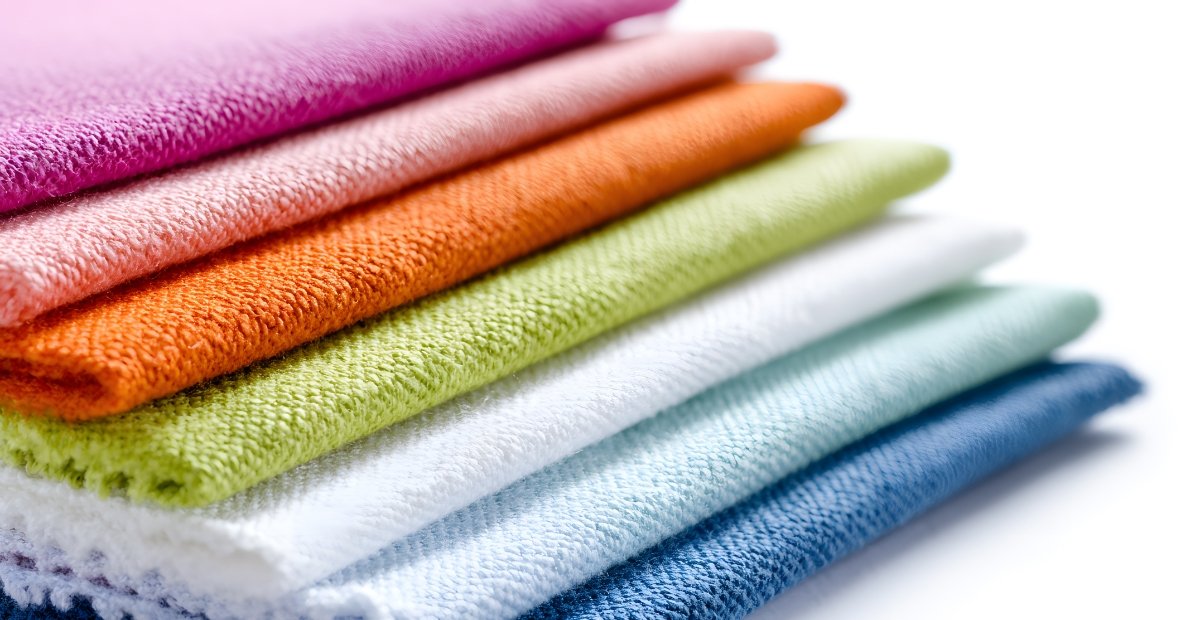 Stack of colorful folded towels arranged in a gradient from pink to dark blue.