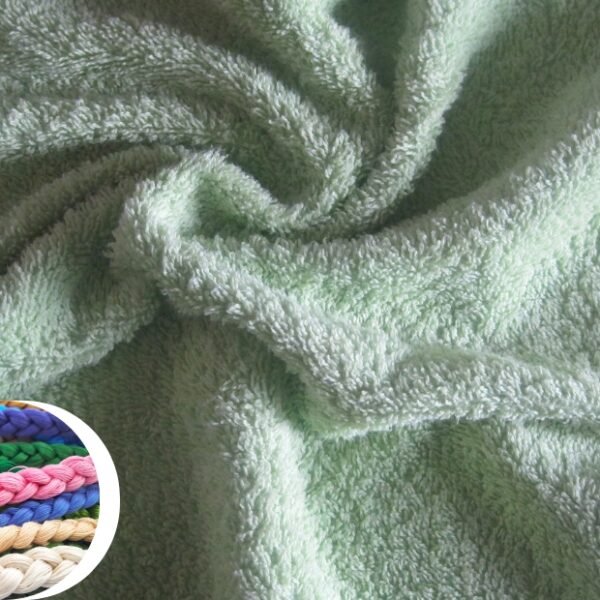 A close-up shot of a soft, plush terry wool fabric in a pale mint-green color, showing dense looped fibers and a cozy, textured surface. Inset at the bottom-left is a circular collage of colorful braided cords (pink, blue, green, purple, yellow, beige) providing a visual contrast.