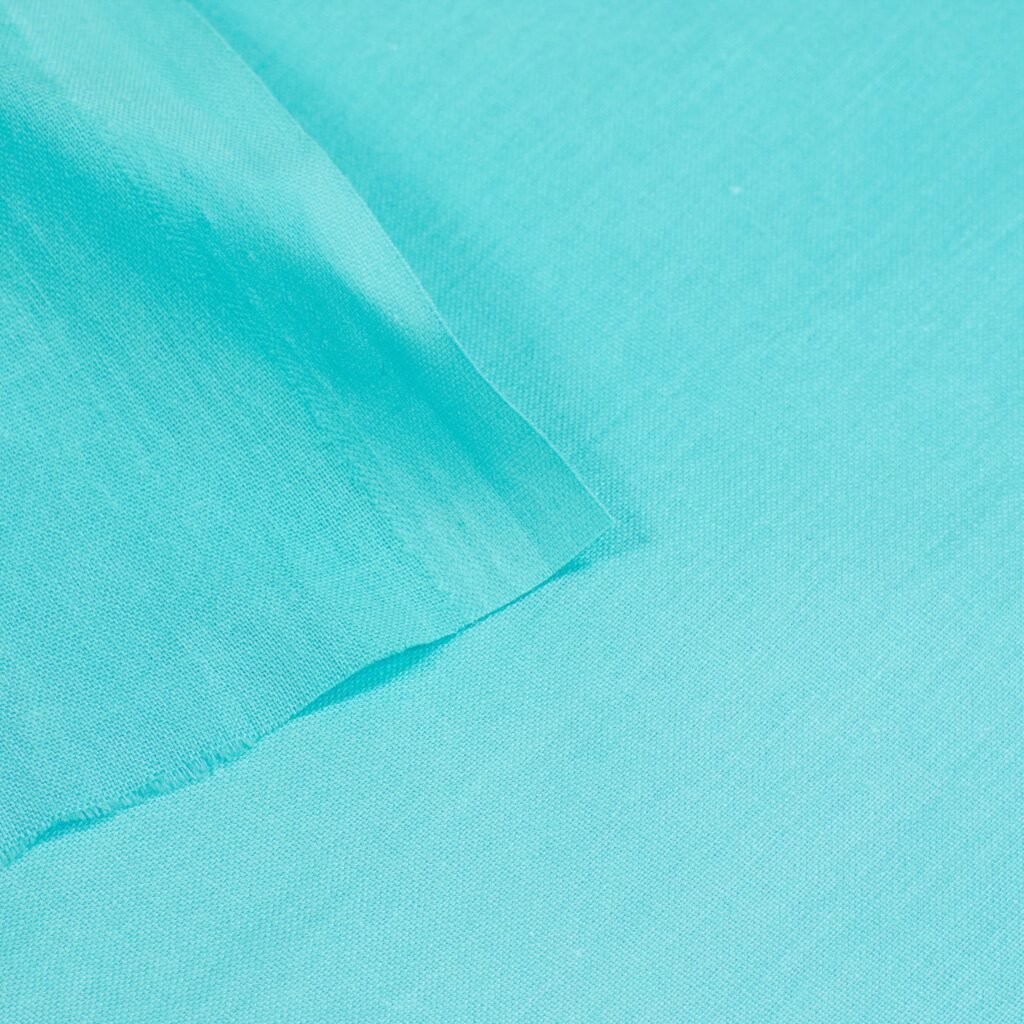 A close-up image showing smooth, finely textured turquoise fabric with soft folds and a gentle sheen.