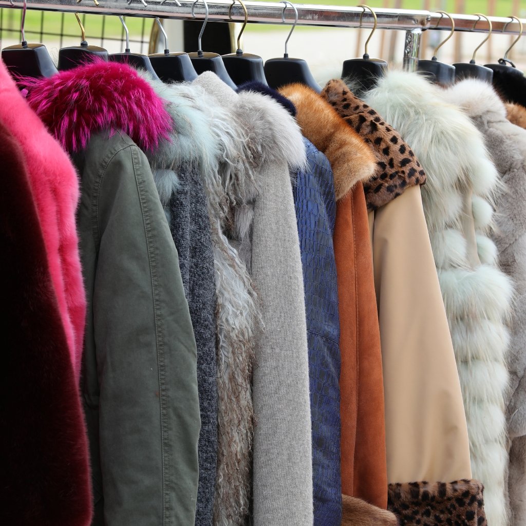 Sheep Wool Clothing: Natural Warmth and Timeless Style 12 A row of coats on hangers featuring various textures and colors, including faux fur collars and leopard print accents, hanging on a clothing rack outdoors.