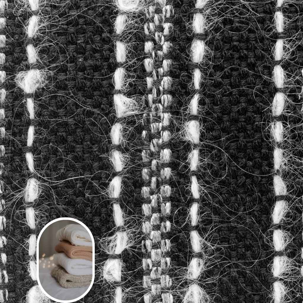 Close-up of a black-and-white boucle wool fabric with looped, irregular yarns creating textured vertical stripes.