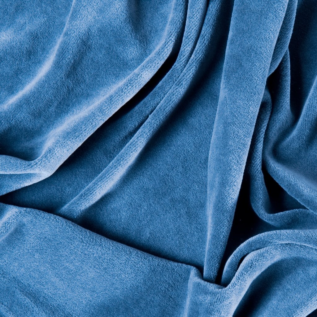 Close-up of soft, blue velvet fabric with flowing folds and shadows."
Caption: "Luxurious blue velvet draped in elegant folds.