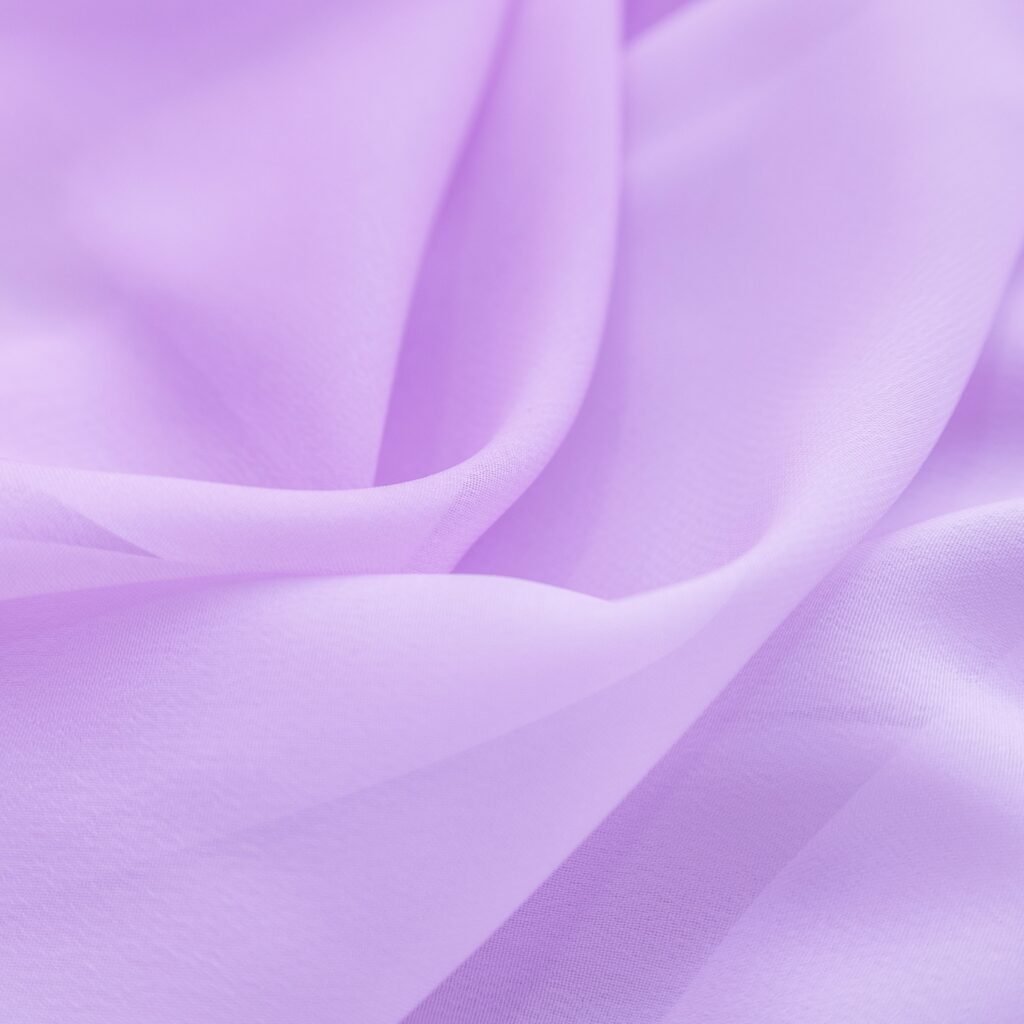 A soft, flowing lavender chiffon fabric with delicate, semi-sheer drapes and gentle folds.