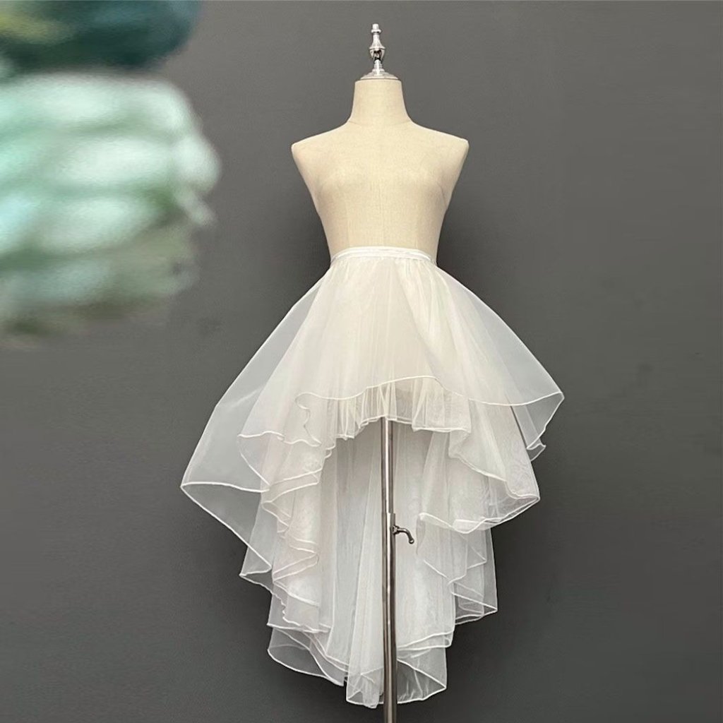 White Organza Fabric: Elegant Style for Dresses and Interiors 21 "Mannequin wearing a white high-low tulle skirt with multiple layered tiers, displayed on a stand against a gray background.