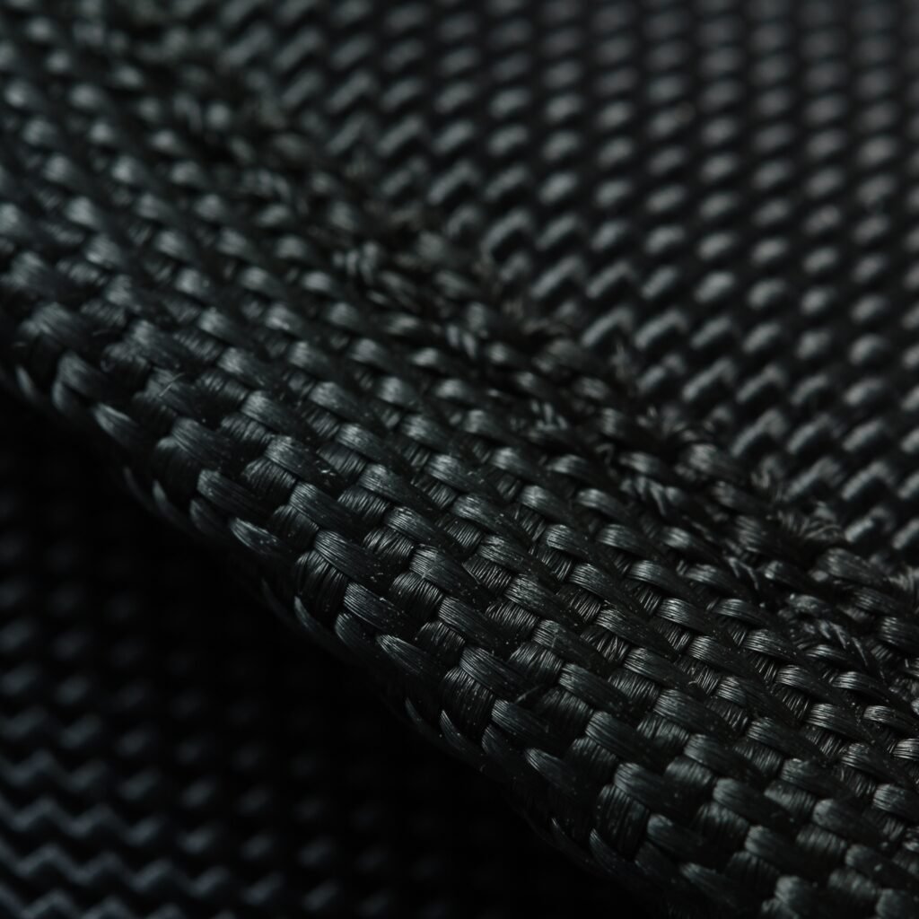 A close-up macro photograph of black nylon fabric showing a tight, interwoven weave pattern with a slight sheen.