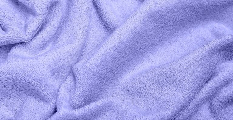A close-up view of soft, plush blue fabric with gentle folds and texture.