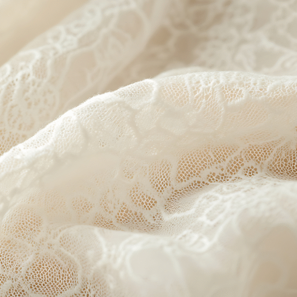 Close-up view of delicate white lace fabric with intricate floral patterns and soft, flowing folds.