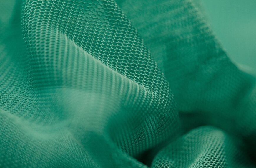 Close-up of green textured fabric or mesh with soft folds and shallow depth of field.