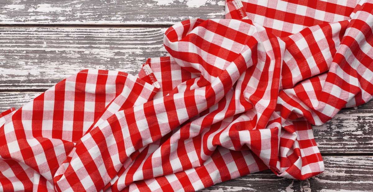 Red and white checkered fabric draped over a weathered wooden surface.