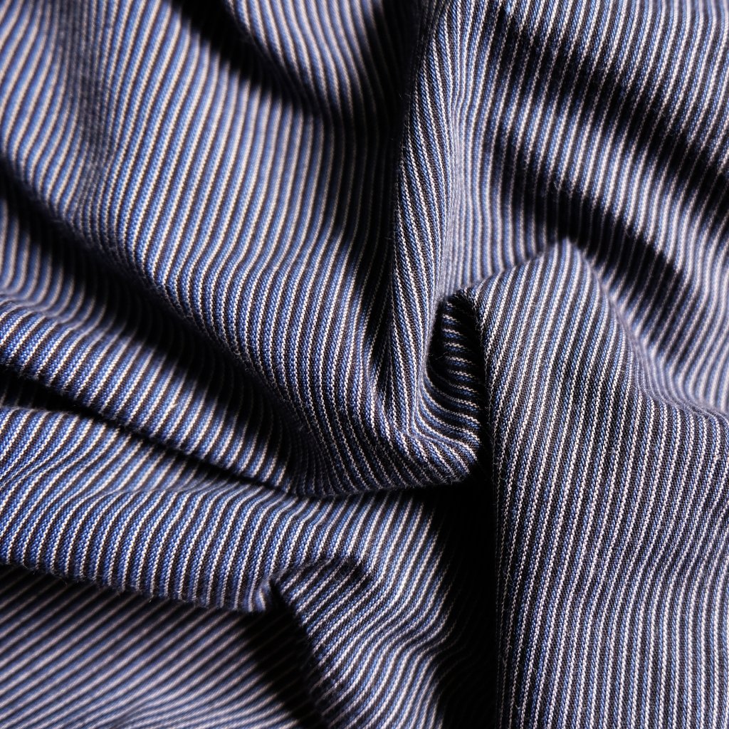 Why Seersucker Cotton Fabric Is Perfect for Summer Outfits 11 A close-up of blue and white pinstripe fabric with folds and creases.