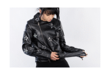 Biker Jacket: Classic Style With Bold Attitude For Look Close-up of a person wearing a black leather biker jacket adorned with silver star patches; the zipper is partially open and the person is pulling at the belt at the waist.
