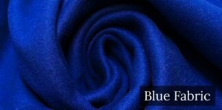 Blue Wool Fabric: Complete Guide to Types Benefits and Uses. A close-up view of soft, royal blue fabric folded into a swirl, with the words “Blue Fabric” displayed in a dark label in the bottom right corner. Blue Wool Fabric
