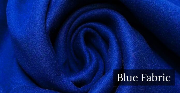 A close-up view of soft, royal blue fabric folded into a swirl, with the words “Blue Fabric” displayed in a dark label in the bottom right corner. Blue Wool Fabric