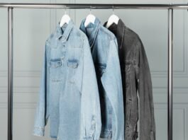 Three denim jackets hanging on a metal clothing rack.