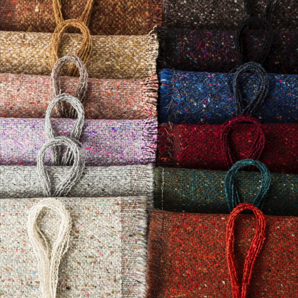 Low Pilling Polyester: A Full Guide to Smooth Durable Fabric 6 A grid of rolled, textured carpets in a wide range of colors and patterns, with looped cords draped over the edges.