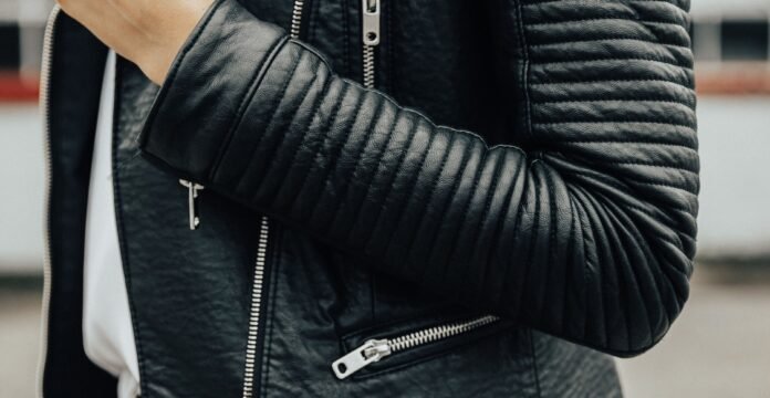 Close-up of a black leather biker jacket with quilted sleeves and silver zippers.