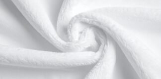 Fleece Fabric: Lightweight Warmth for Everyday Comfort A close-up of a soft, white textured fabric (like a towel or fleece) folded and twisted in a gentle spiral.
