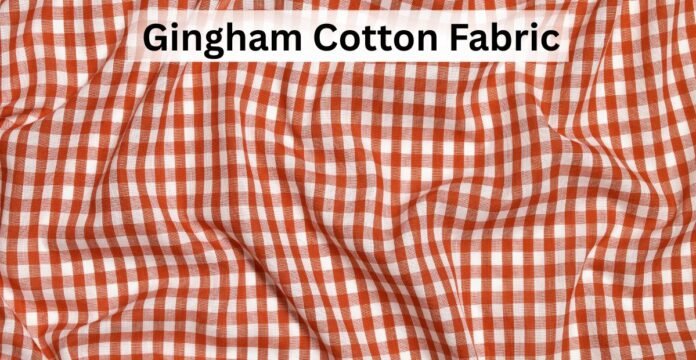 Close-up view of gingham cotton fabric in a red and white checkered pattern with soft folds.