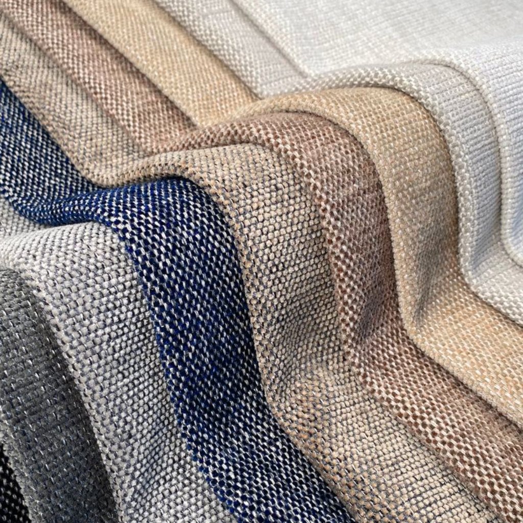 High-Tenacity Polyester: Strength, Durability & Key Benefits 8 A close-up view of overlapping woven fabric swatches in various neutral colors (creams, beiges, taupes) and a dark denim blue, displaying textured, coarse weaves.