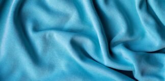 IS RAYON A GOOD FABRIC CHOICE COMFORT & STYLE A close-up shot of smooth, bright blue fabric with soft folds and gentle shadows.