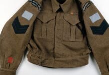 Military Field Leather Jacket: Strong Style for Daily Wear "Brown leather military field jacket with patch insignia on sleeves, two chest pockets, ribbon bar on left chest, and visible rank chevrons on sleeve; appears to be a WW2-era style."