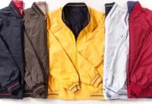 Performance Track Jacket: Top Features Athletes Should Know. A row of six lightweight jackets in different colors (navy, brown, mustard yellow, light gray, and red) laid flat side by side with their zippers and cuffs visible. Performance Track Jacket