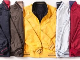 A row of six lightweight jackets in different colors (navy, brown, mustard yellow, light gray, and red) laid flat side by side with their zippers and cuffs visible. Performance Track Jacket