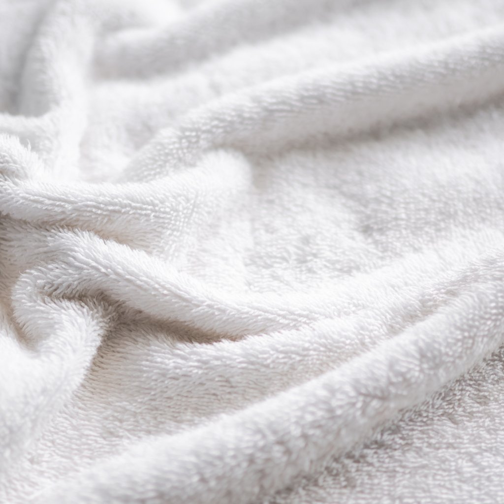 A close-up view of soft, white terry cloth fabric with gentle folds and texture. Softness and Comfort