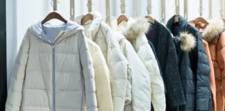 Top 20 Types of Overcoats Every Stylish Man Should Know A row of insulated winter jackets hanging on wooden hangers against a light background.